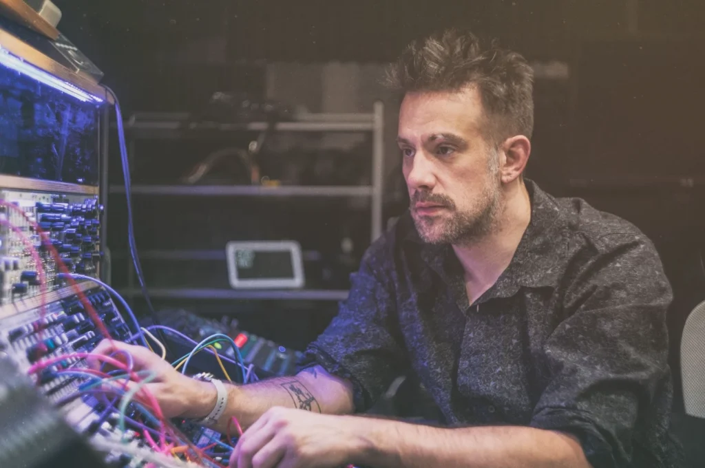 Benn Jordan sitting at an audio workstation tinkering with the dials