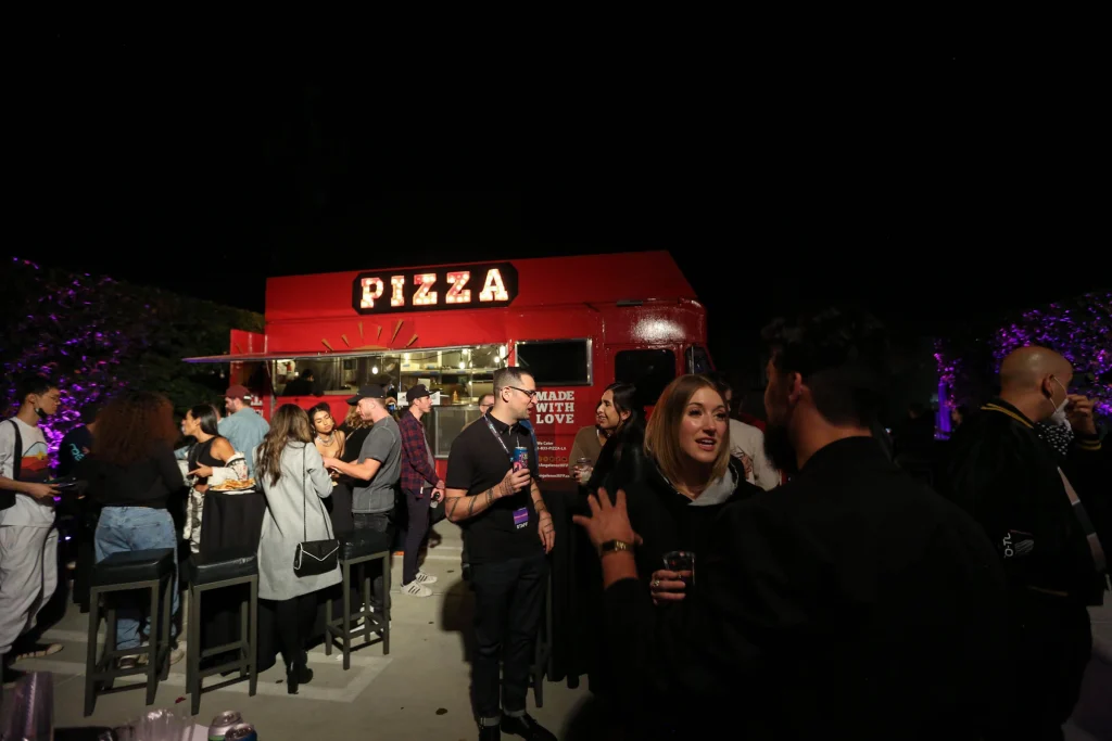 People talking, standing in front of a red pizza food truck