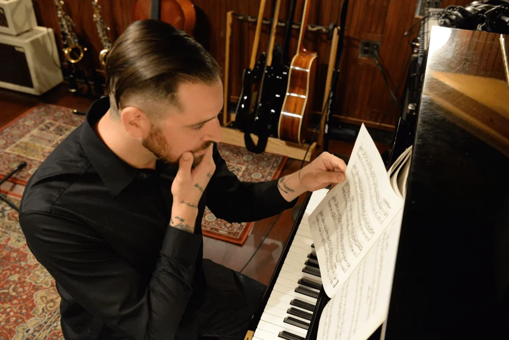 Roman Molino Dunn sitting at a piano looking through sheet music
