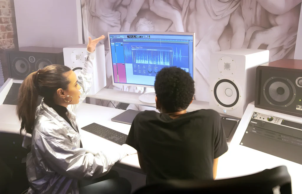 A man and a woman sitting at a desk looking at a monitor