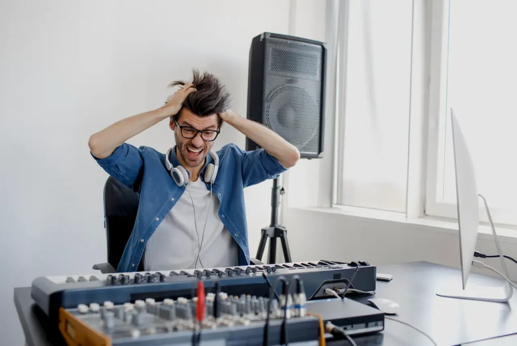 A man sitting by a keyboard with his hands in his hair, visibly agitated