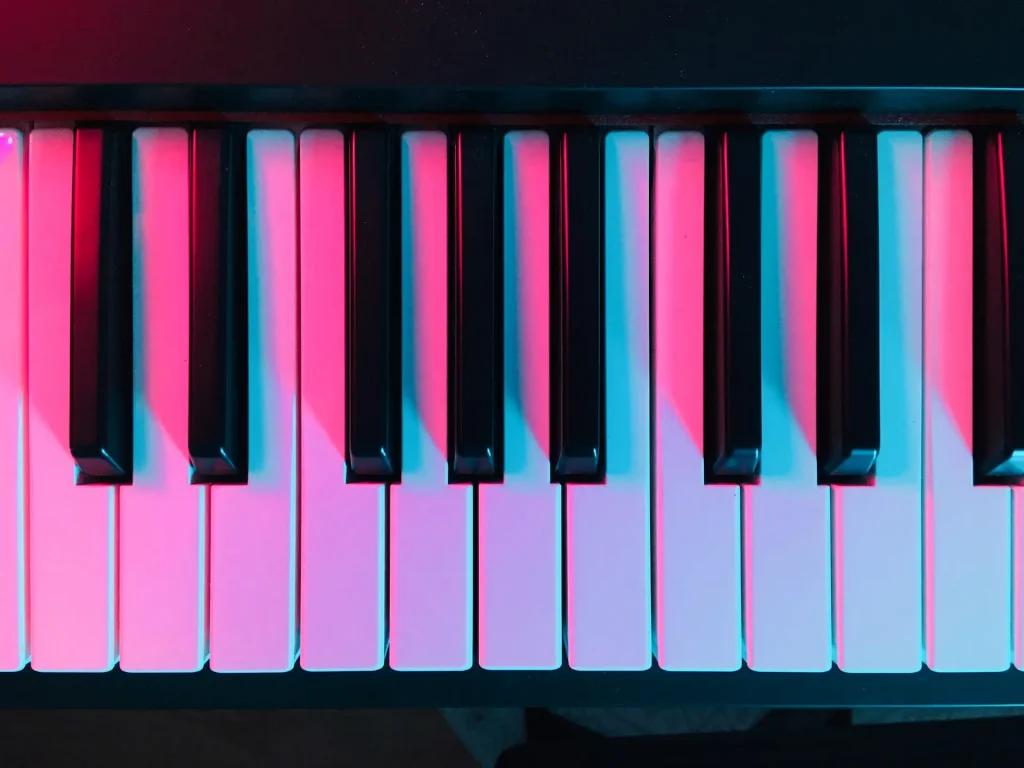 A close up of a piano keyboard bathed in pink light