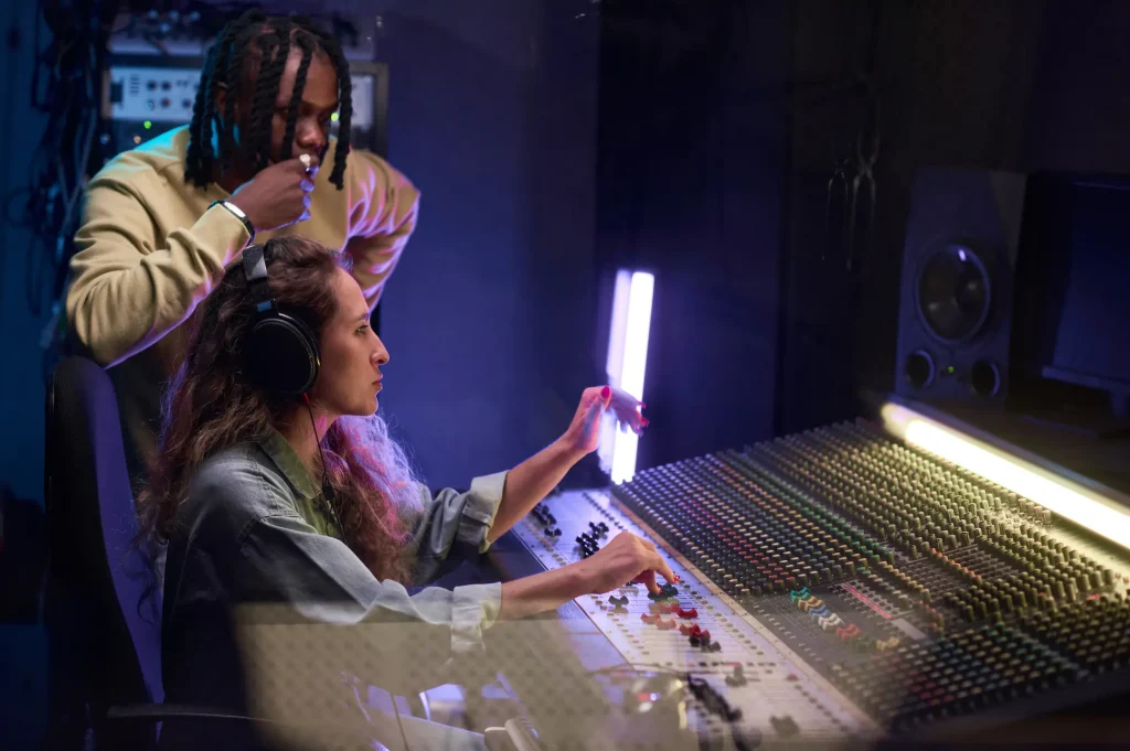 A man and a woman sitting in front of a soundboard mixer