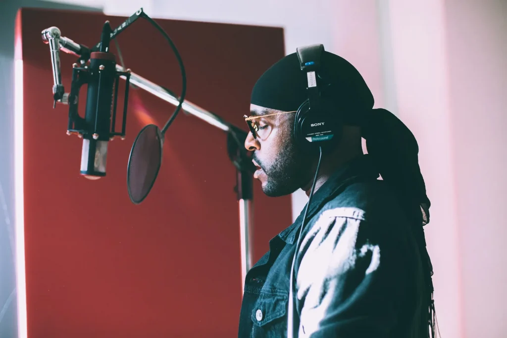 A man wearing headphones standing in front of a studio microphone