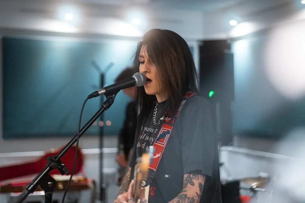 A woman playing the guitar singing into a microphone