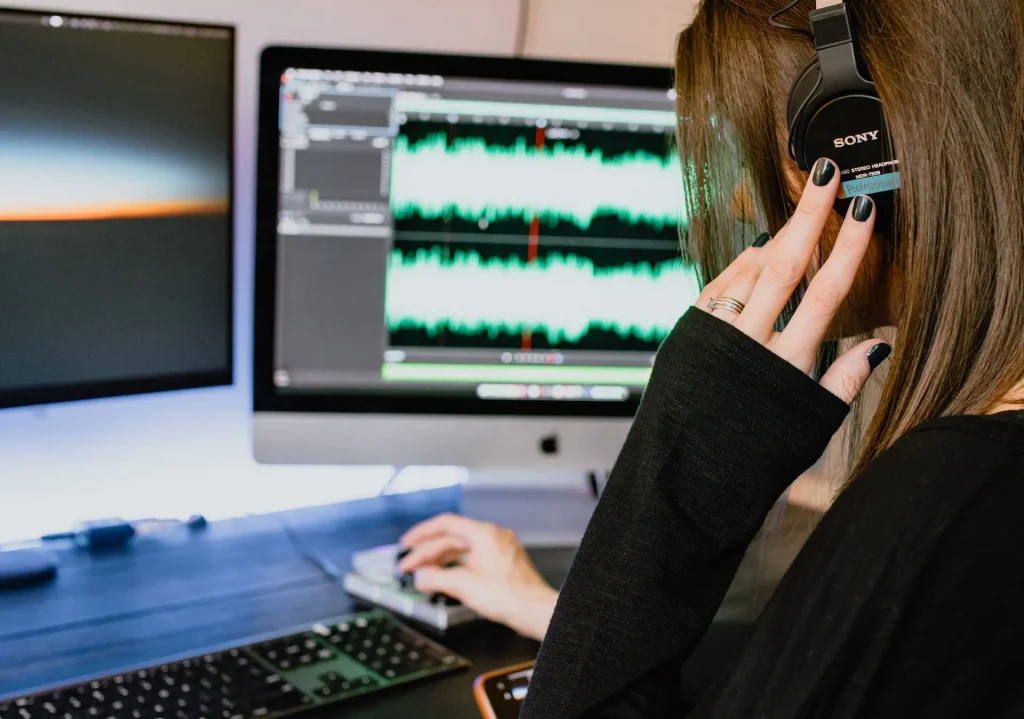 A woman wearing headphones sitting at a desk in front of a computer