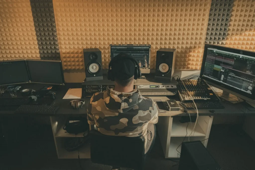 A man sitting at a desk in front of a computer in his home studio