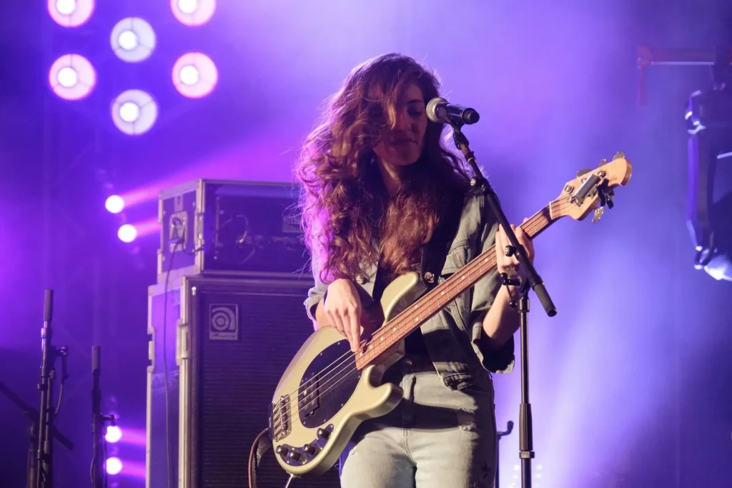 A woman on stage playing the bass guitar