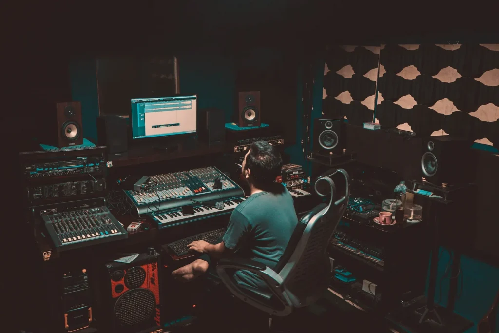 Man in a studio sitting in front of a mixer and computer
