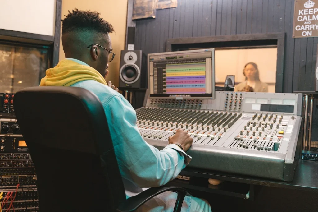 A man sitting in front of a mixing console in a recording studio