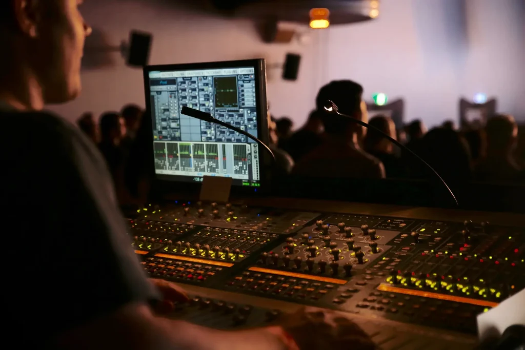 A man monitoring the audio levels from a sound booth. 