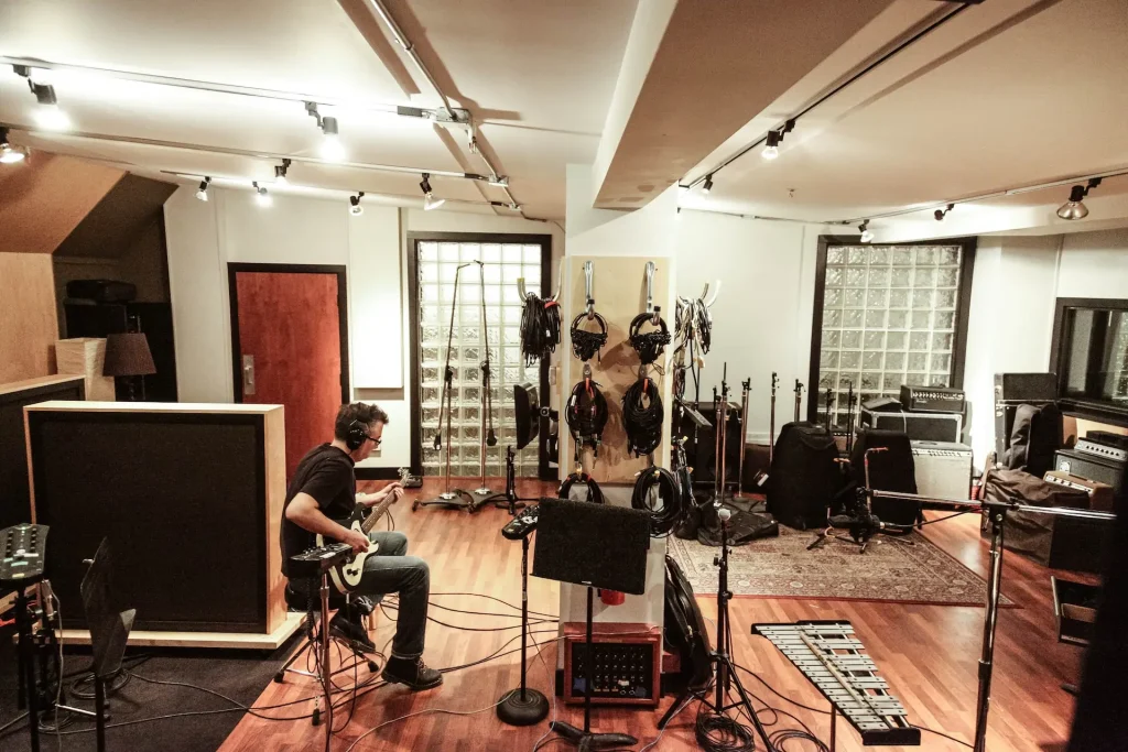 A man playing the guitar in a recording studio