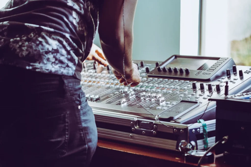 Someone adjusting knobs on a mixing console