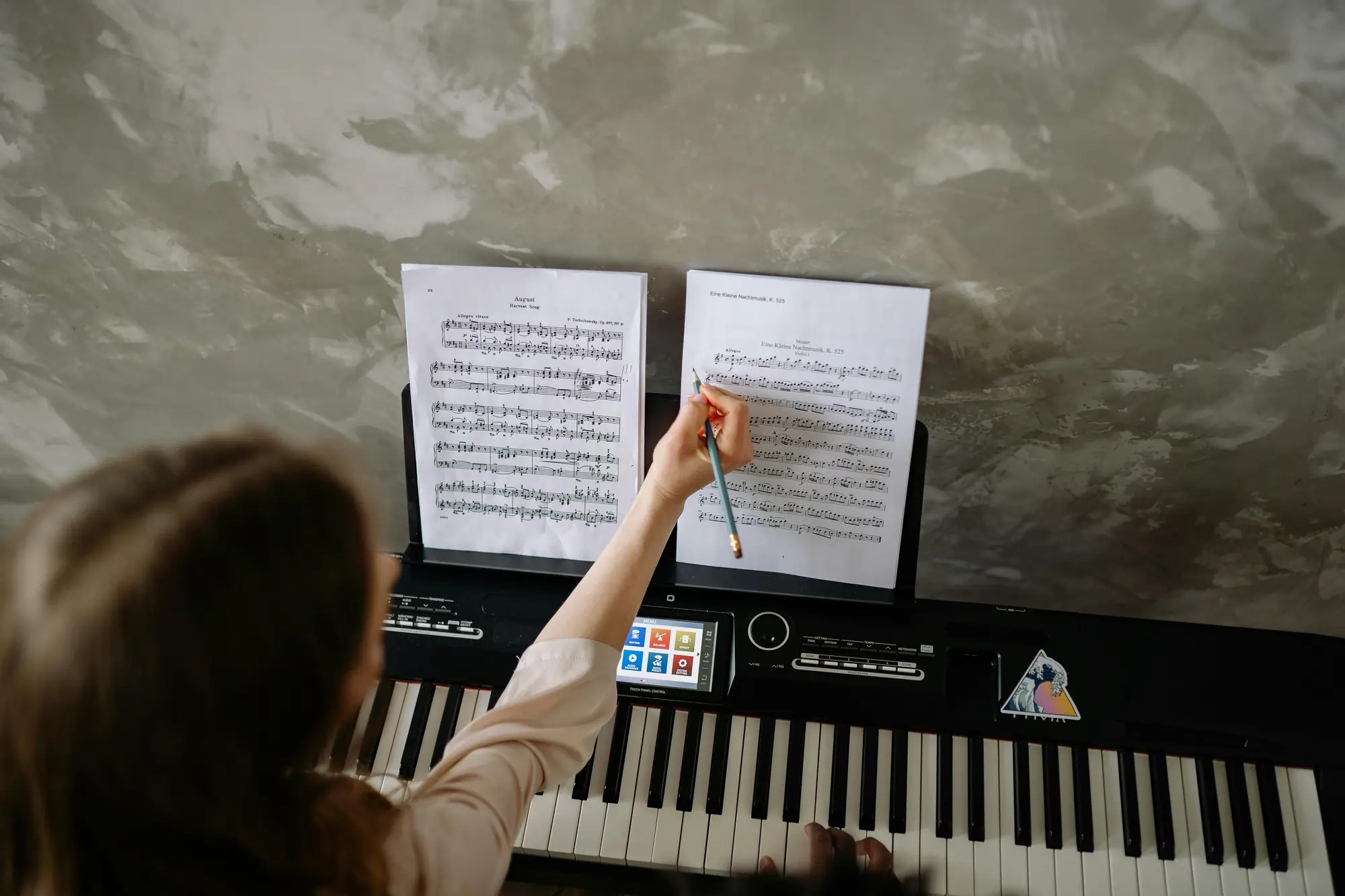 A person sitting in front of a keyboard writing on sheet music