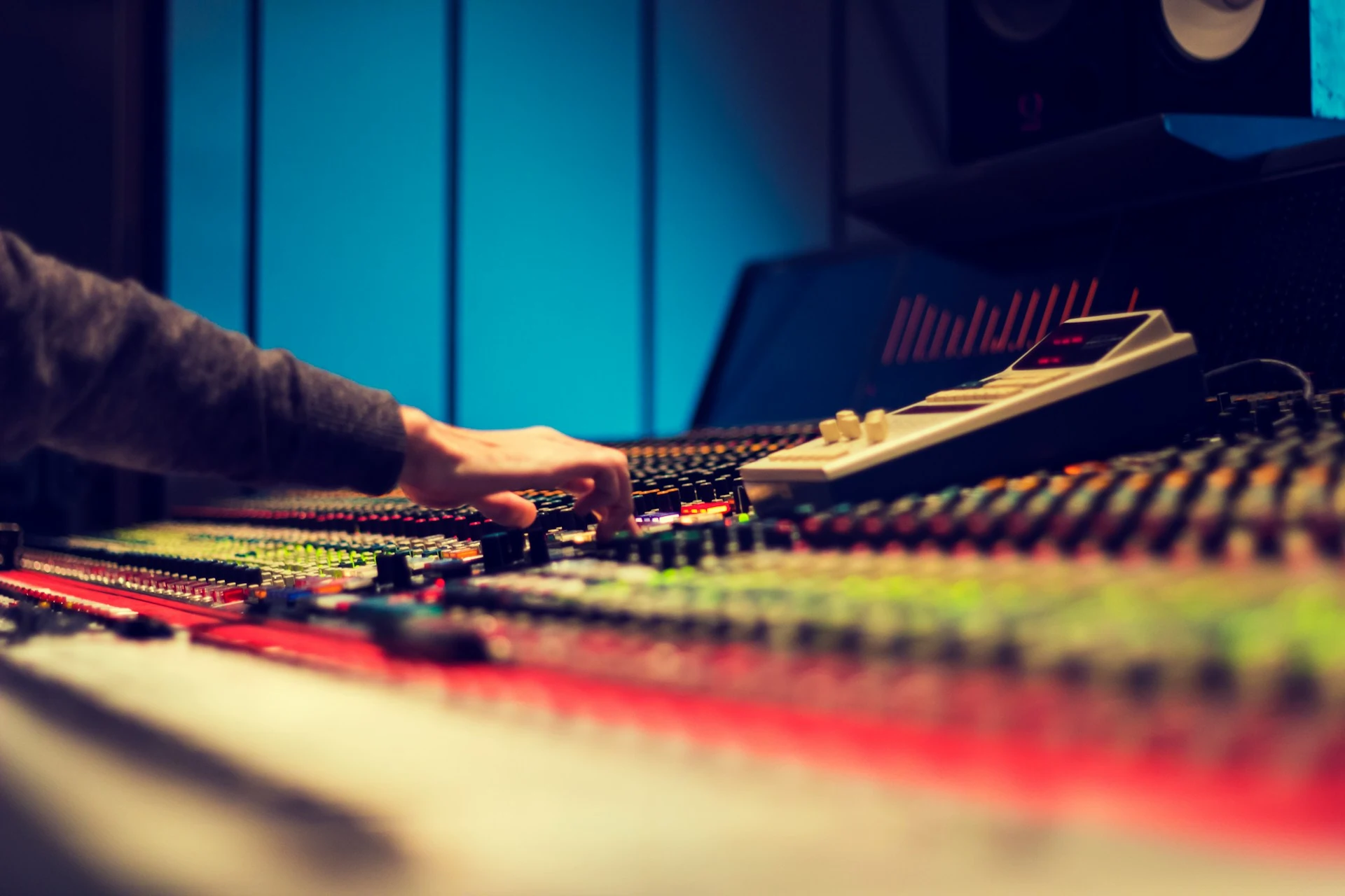 A hand adjusting levels on a mixing console