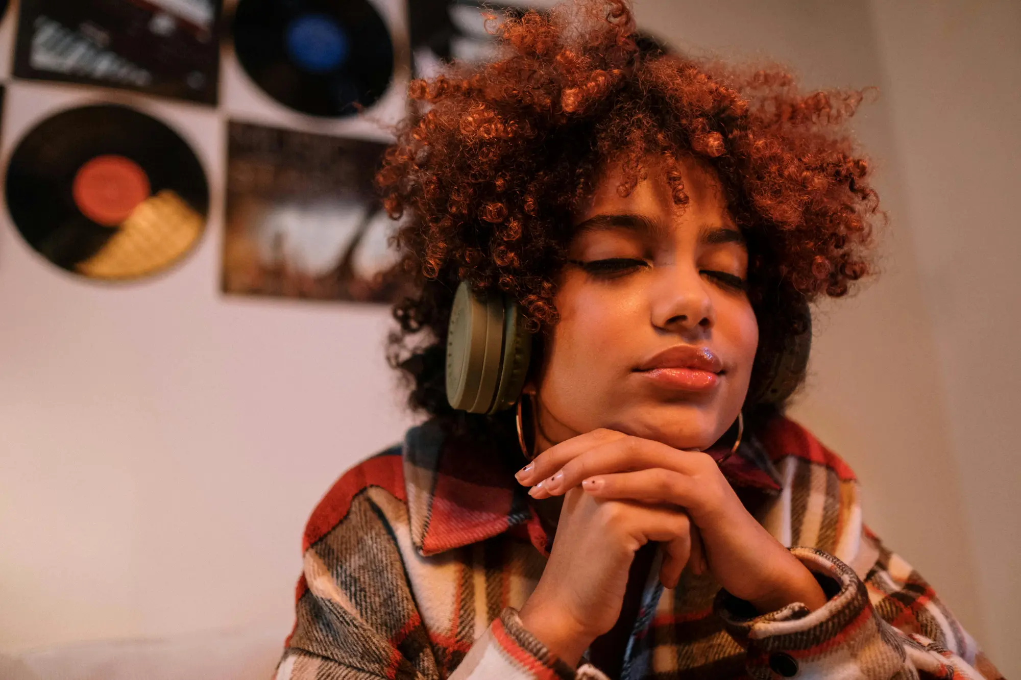 A woman wearing headphone, resting her had on her hand with her eyes closed