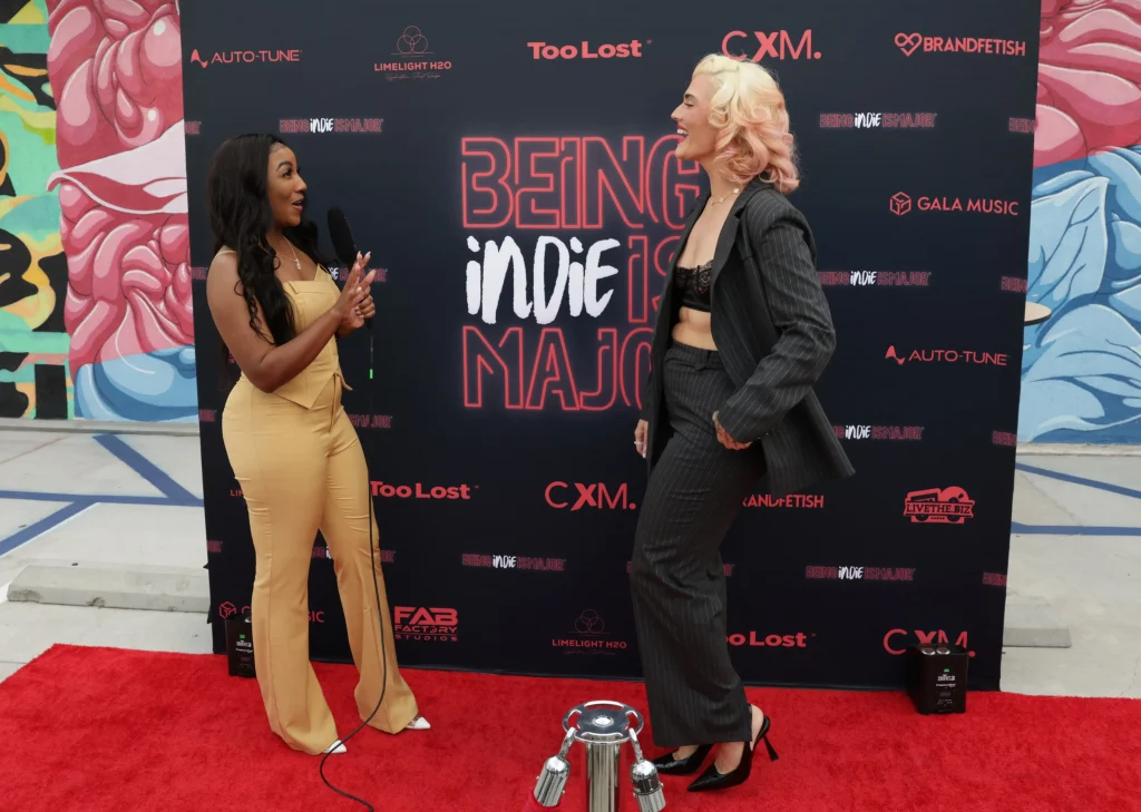 A woman interviewing another woman on a red carpet